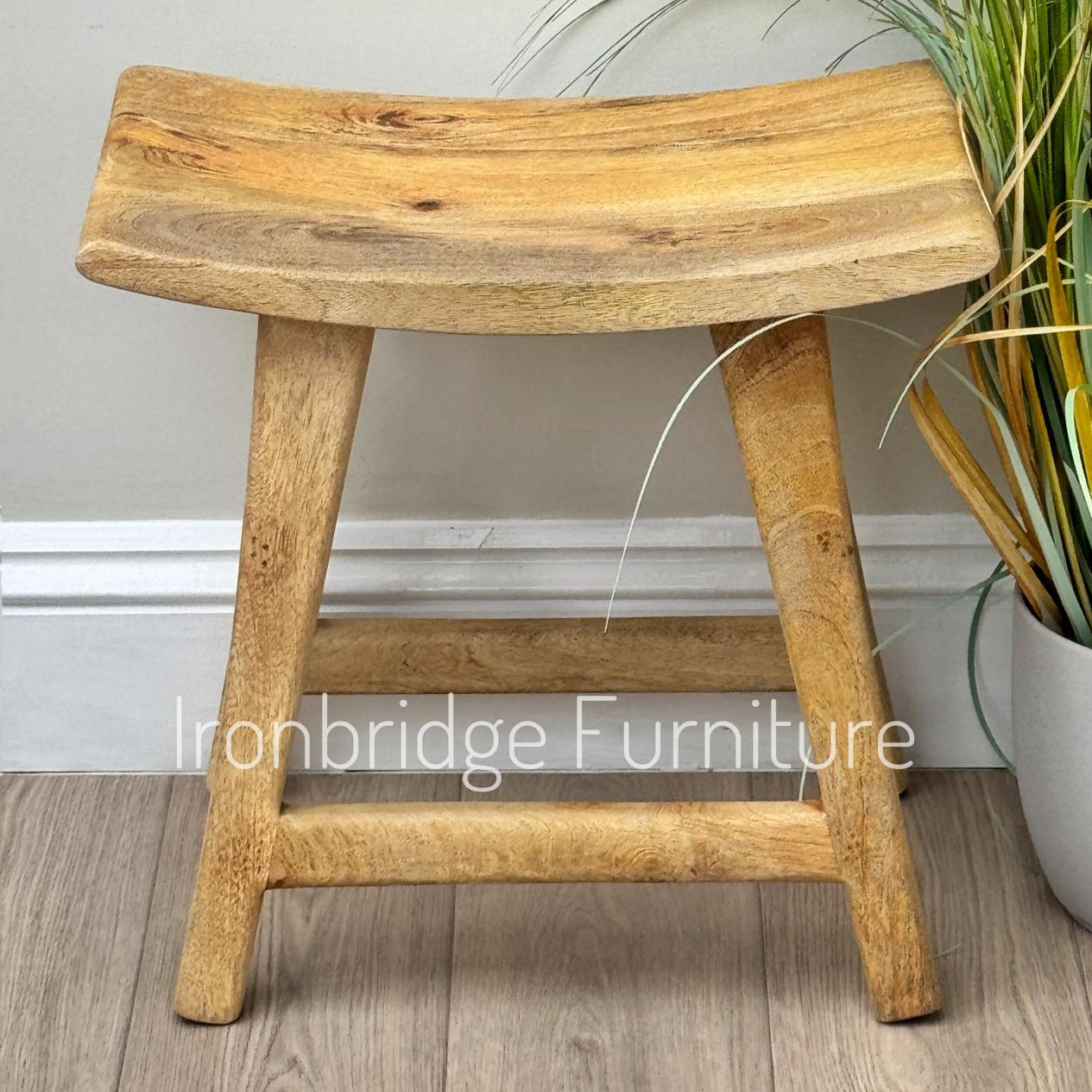 Curved rustic Mango wood stool single (light). Front on.