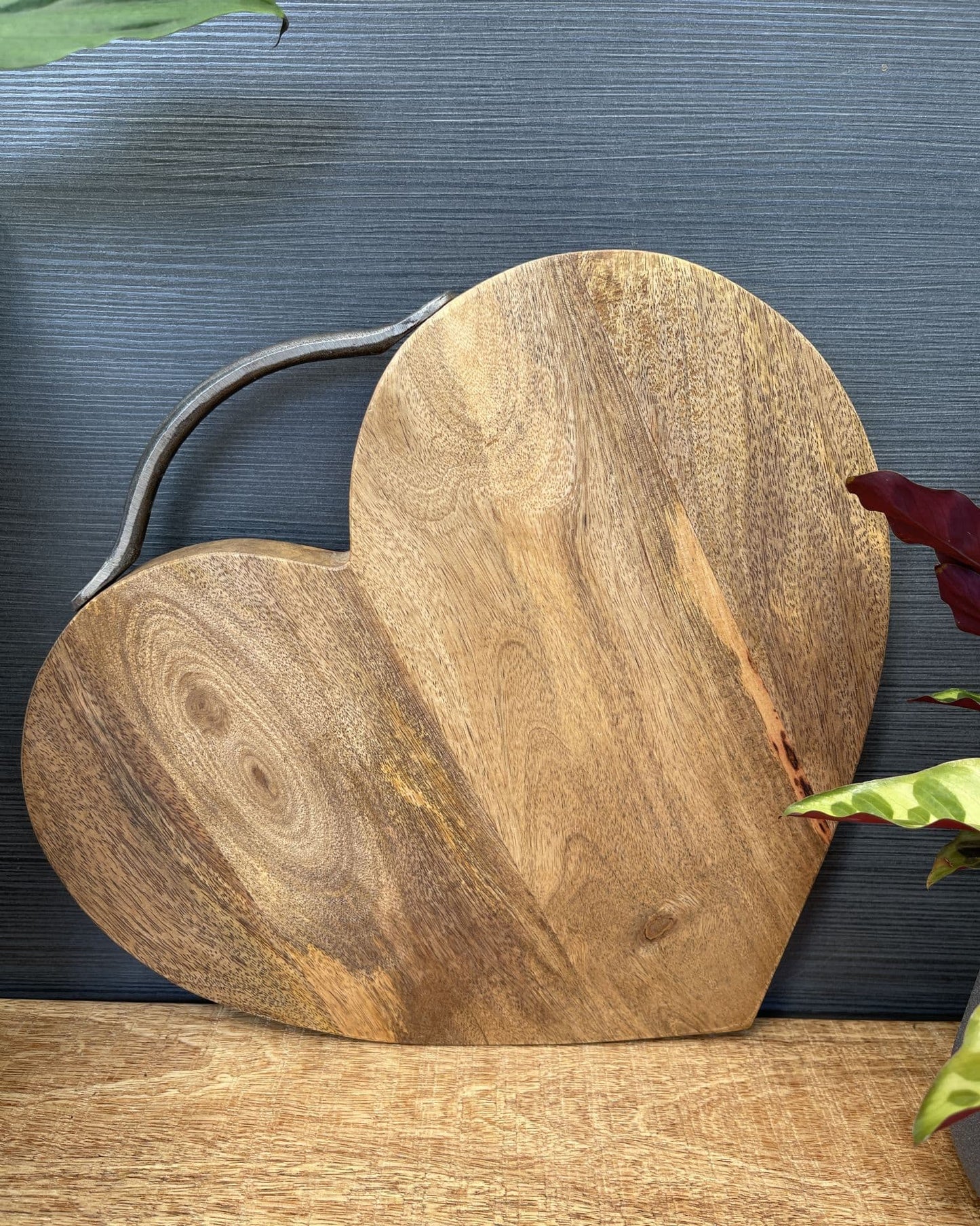 Large heart shaped Mango wood chopping board. With handle, stood up.