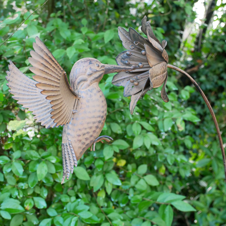 Bronze sculpture of a hummingbird and flower against a green leafy background