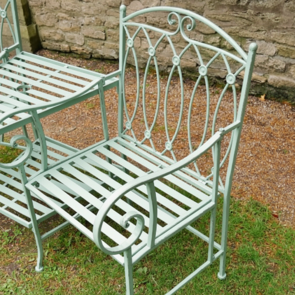 Wrought iron garden bench on grass with stone wall background