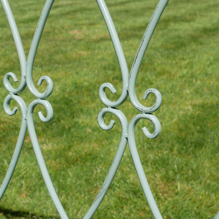 Decorative metal gate with intricate designs on a grassy background