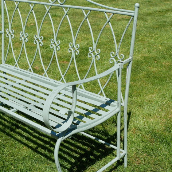 Wrought iron garden bench on a grassy background