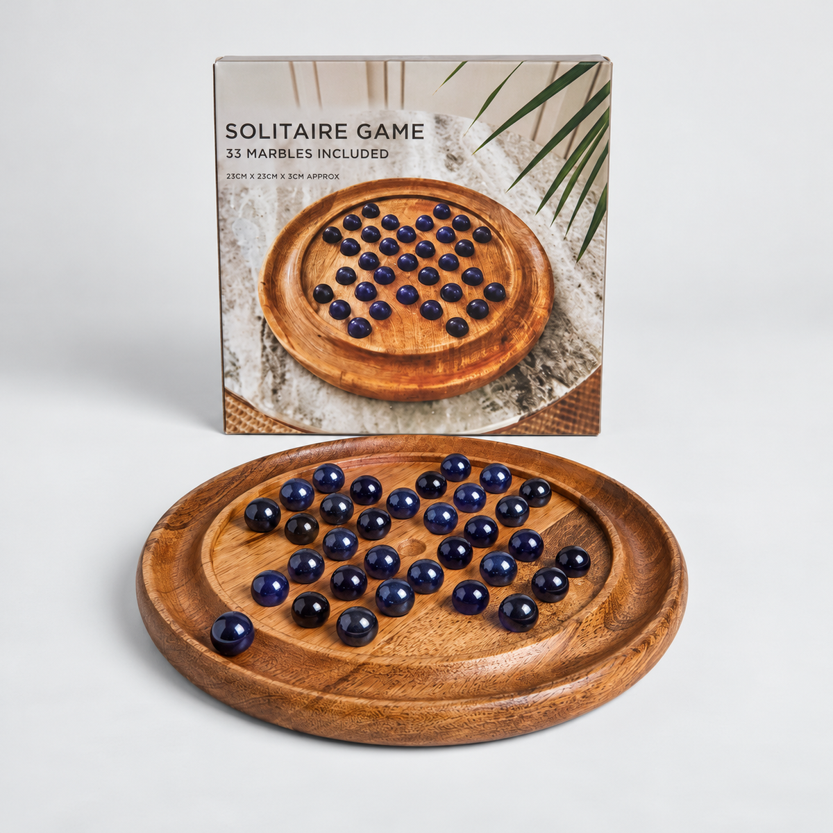 A wooden solitaire game board with dark blue glass marbles, shown in front of its product packaging box on a light gray background.