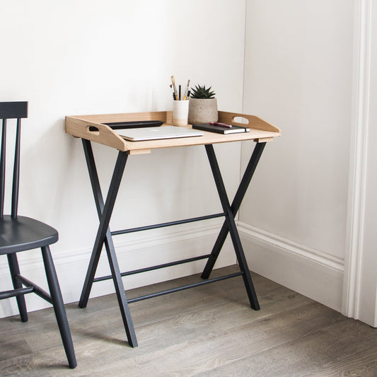 Small wooden desk with black metal legs against a white wall.