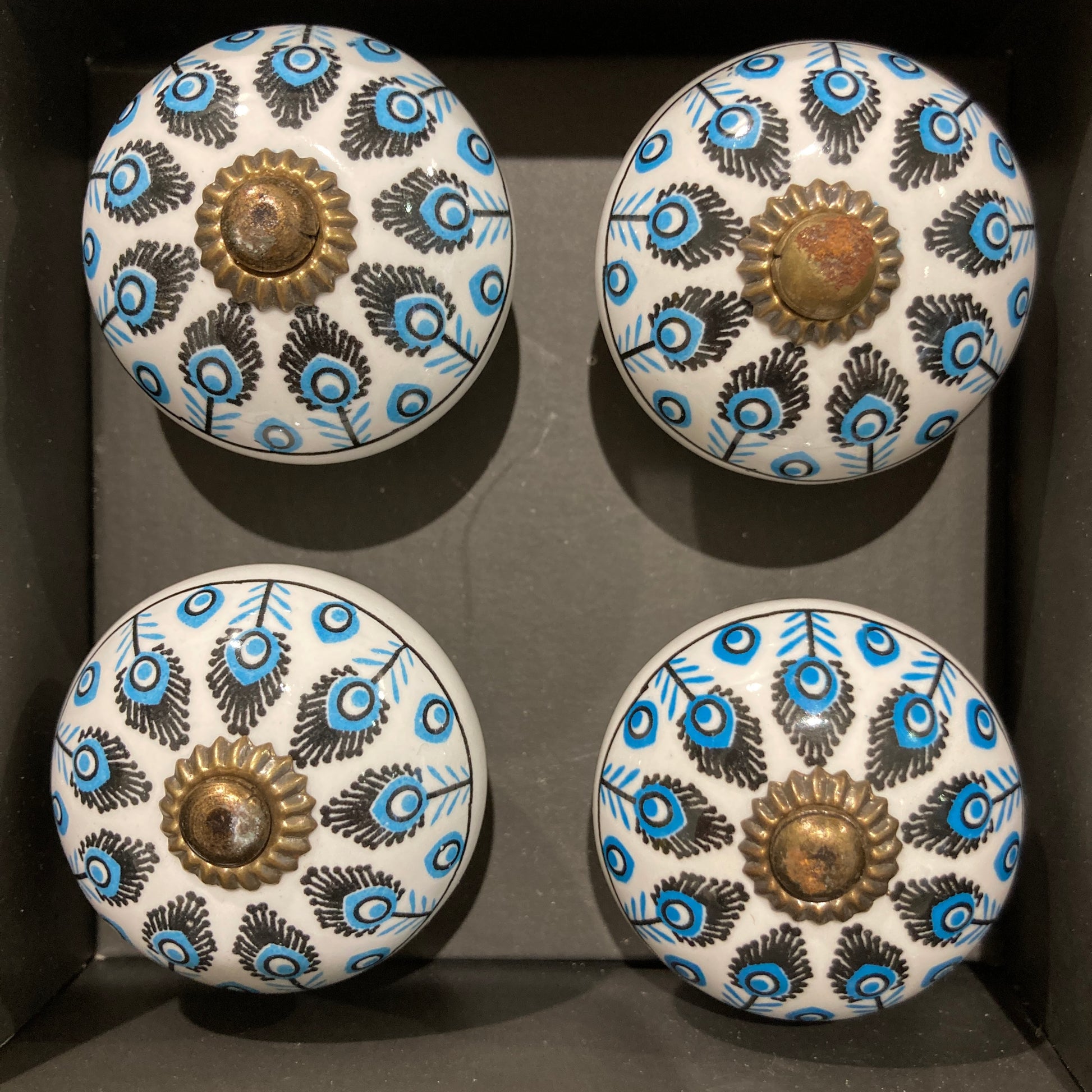 Set of 4 hand painted ceramic knob handles. Feather pattern in box.