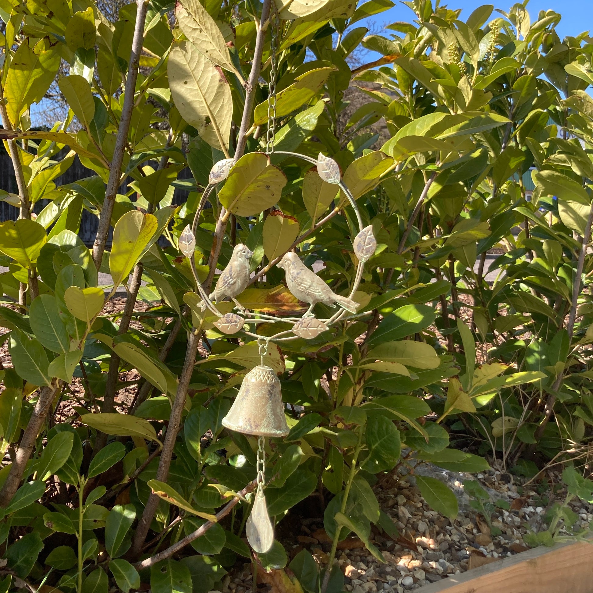 Hanging bird wind chime / bell. Shown in a bush. 