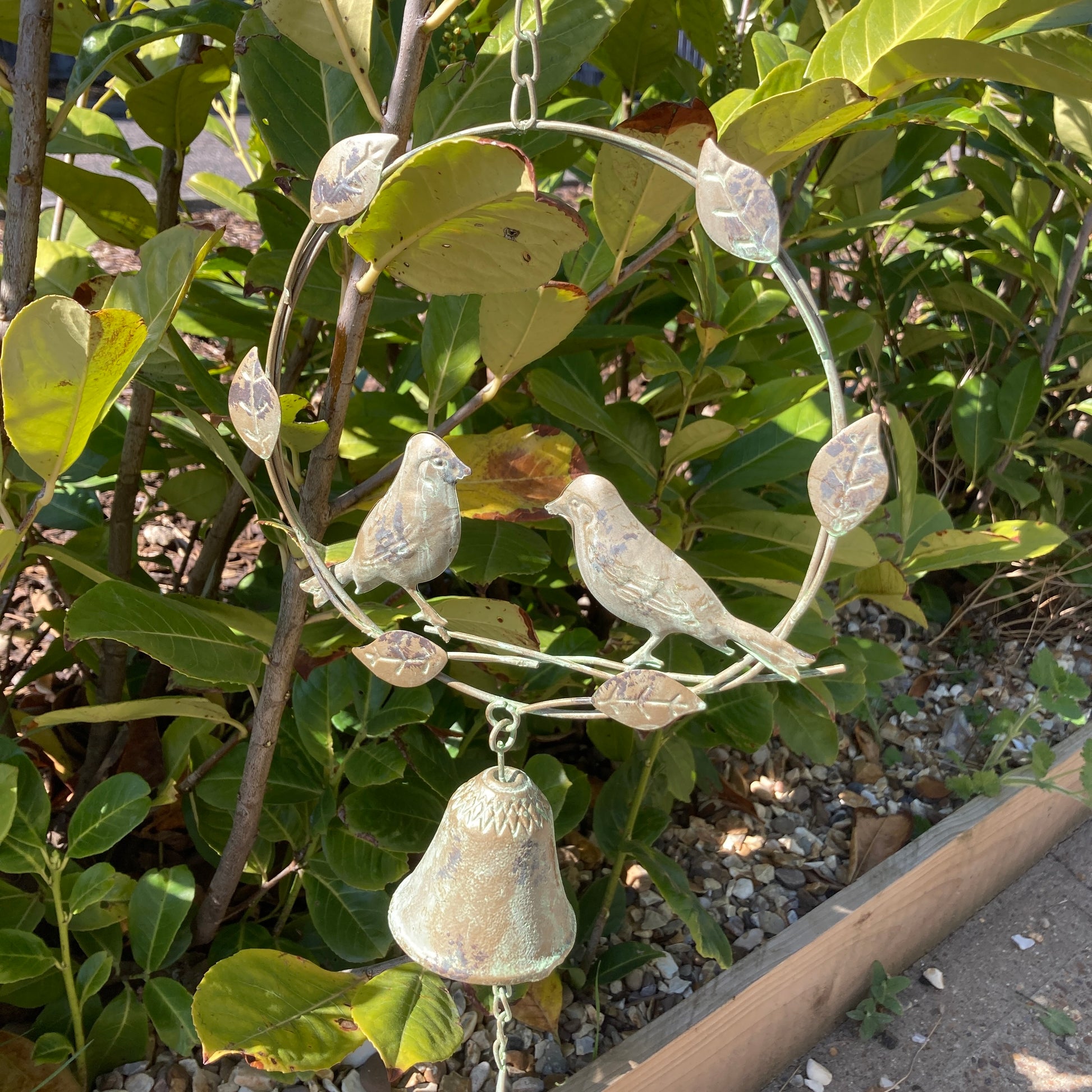 Hanging bird wind chime / bell - shows whole ornament in a bush.