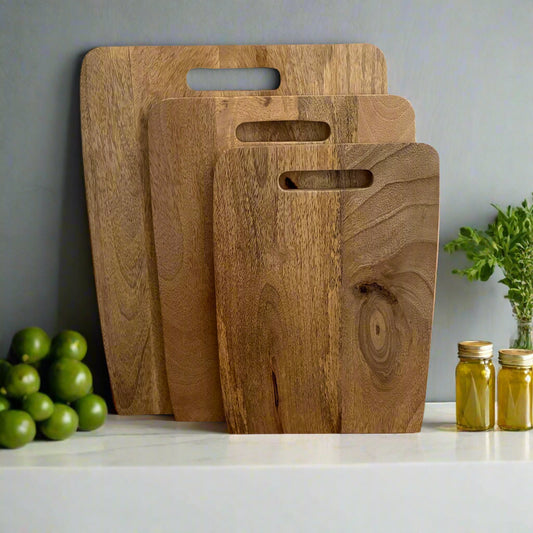 Three wooden cutting boards of different sizes on a wooden surface with a neutral background