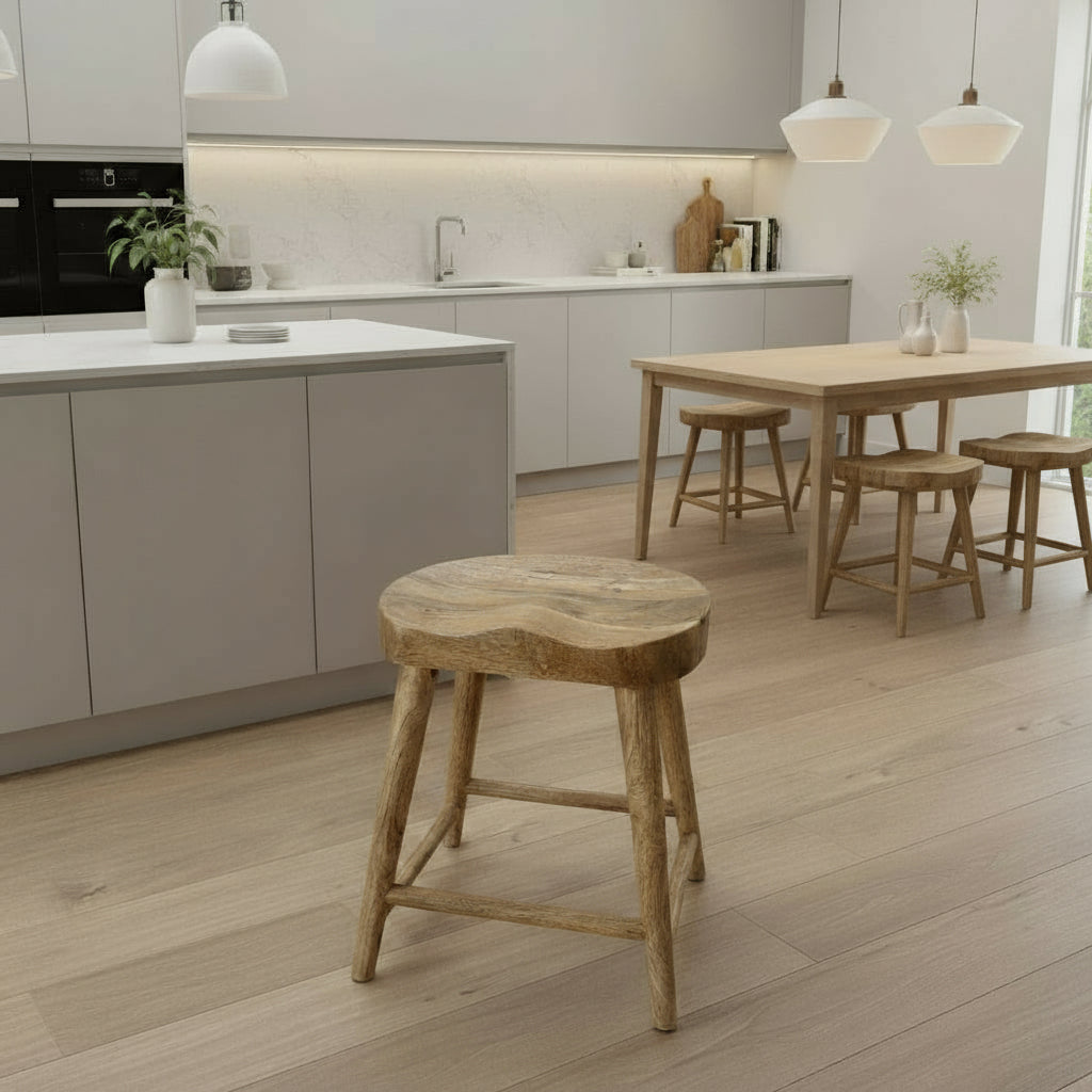 Wooden stool on a wooden floor with a white paneled wall in the background