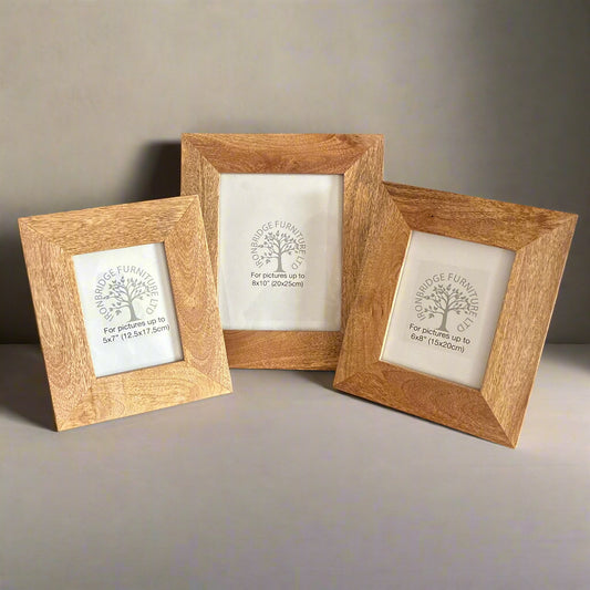 Three wooden picture frames with engraved designs on a neutral background