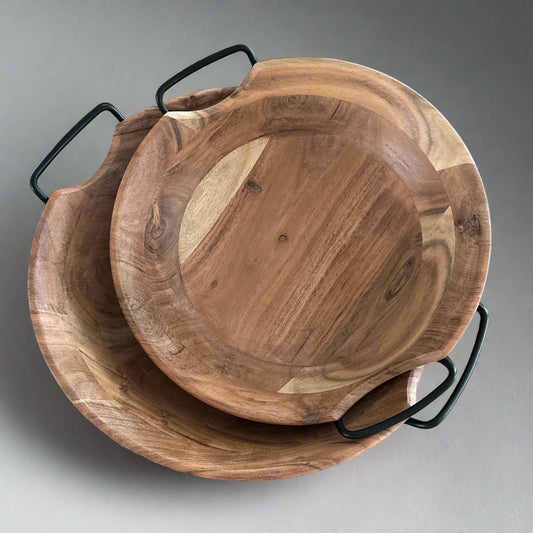 Two wooden bowls with black handles on a light wood surface.