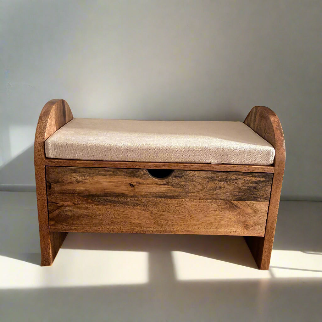 Wooden bench with a cushion on a wooden floor against a white wall