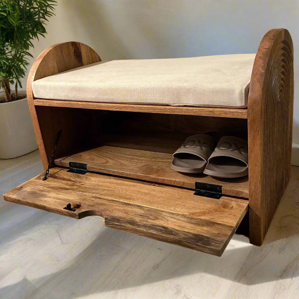 Wooden shoe bench with cushioned seat and open drawer showing shoes on a wooden floor.