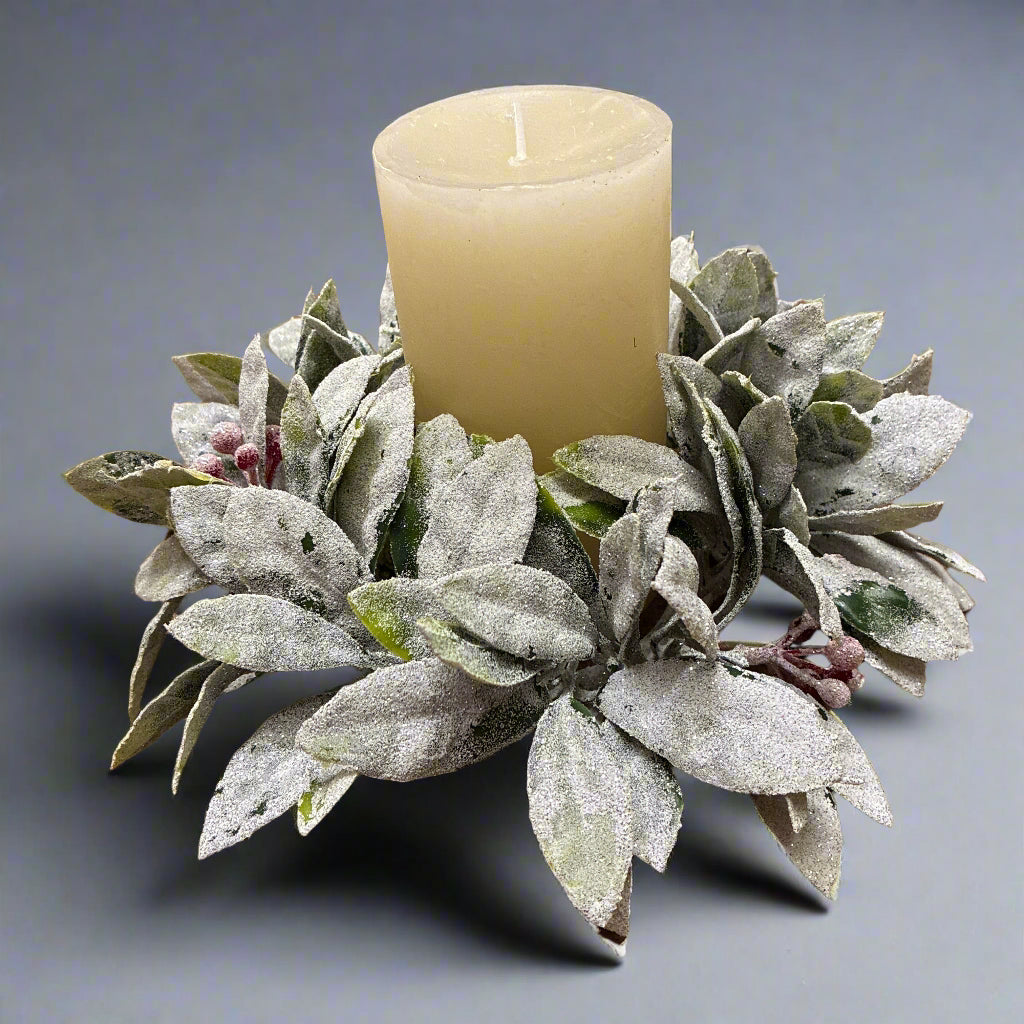 Frosted leaf wreath with a candle in the center on a wooden surface