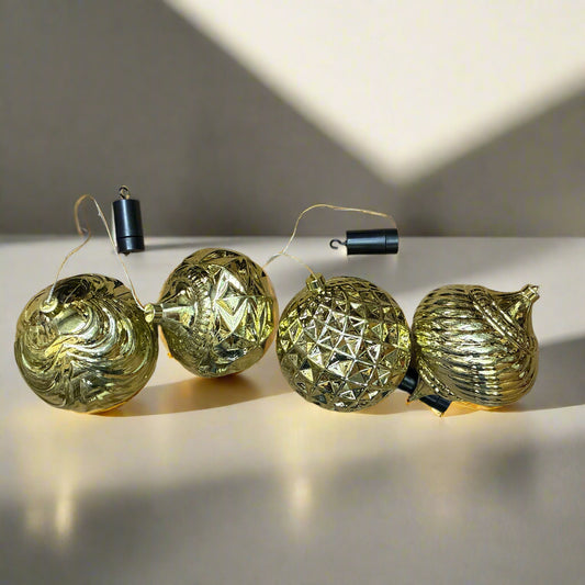 Set of gold Christmas ornaments on a reflective surface with a neutral background