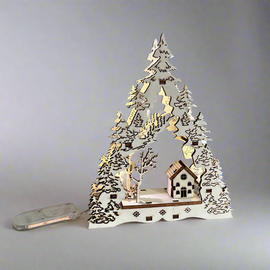 Decorative LED Christmas tree with houses and trees on a wooden base against a grey background