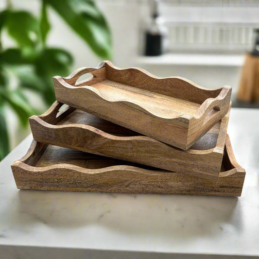 Set of three wooden trays stacked on a wooden floor