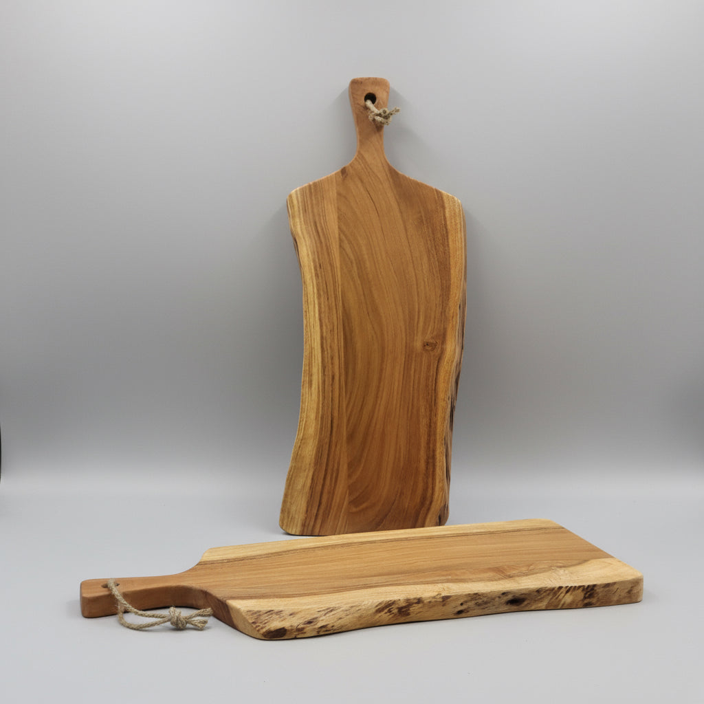 Two wooden cutting boards on a surface with cardboard boxes in the background.