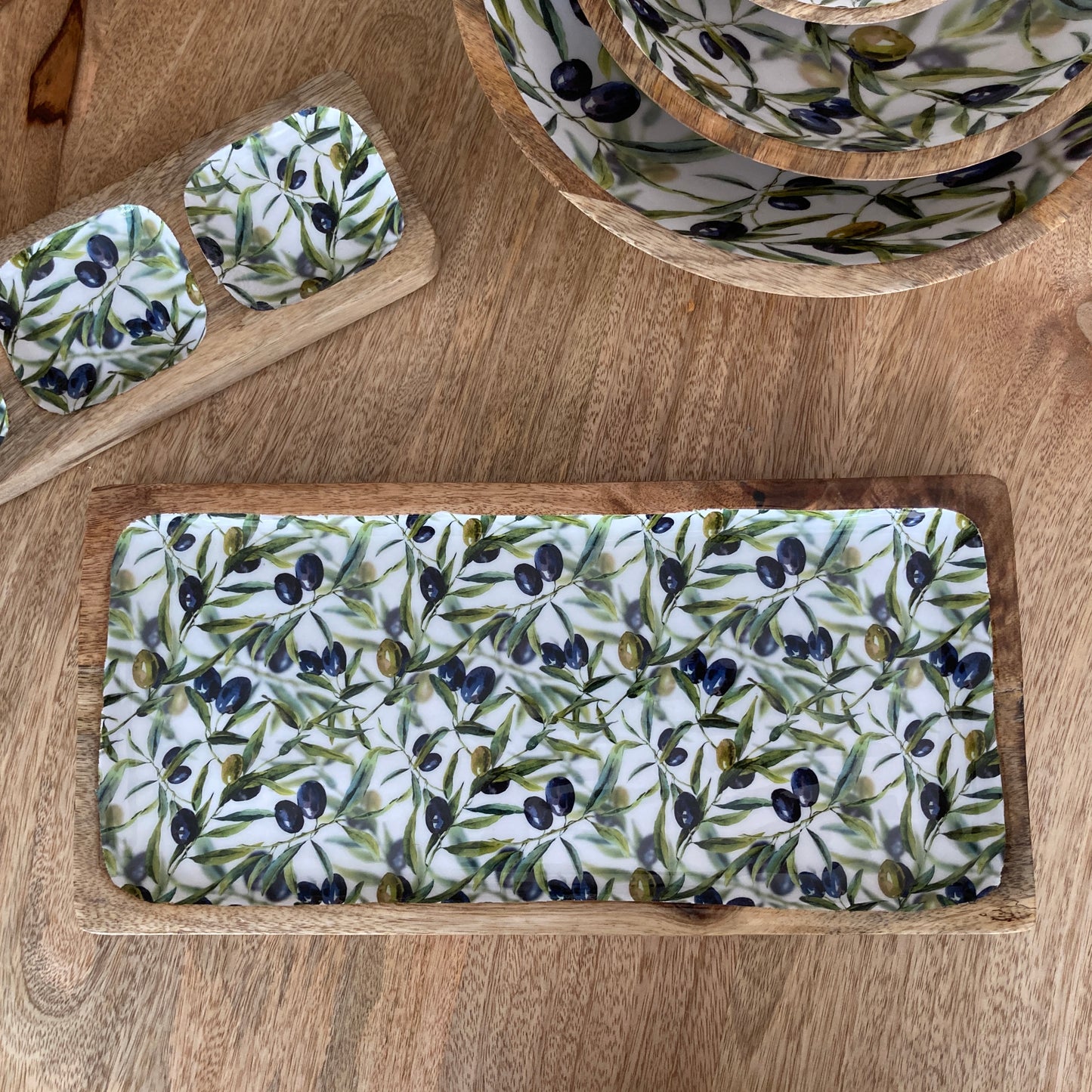 Wooden tray with olive pattern on a wooden surface
