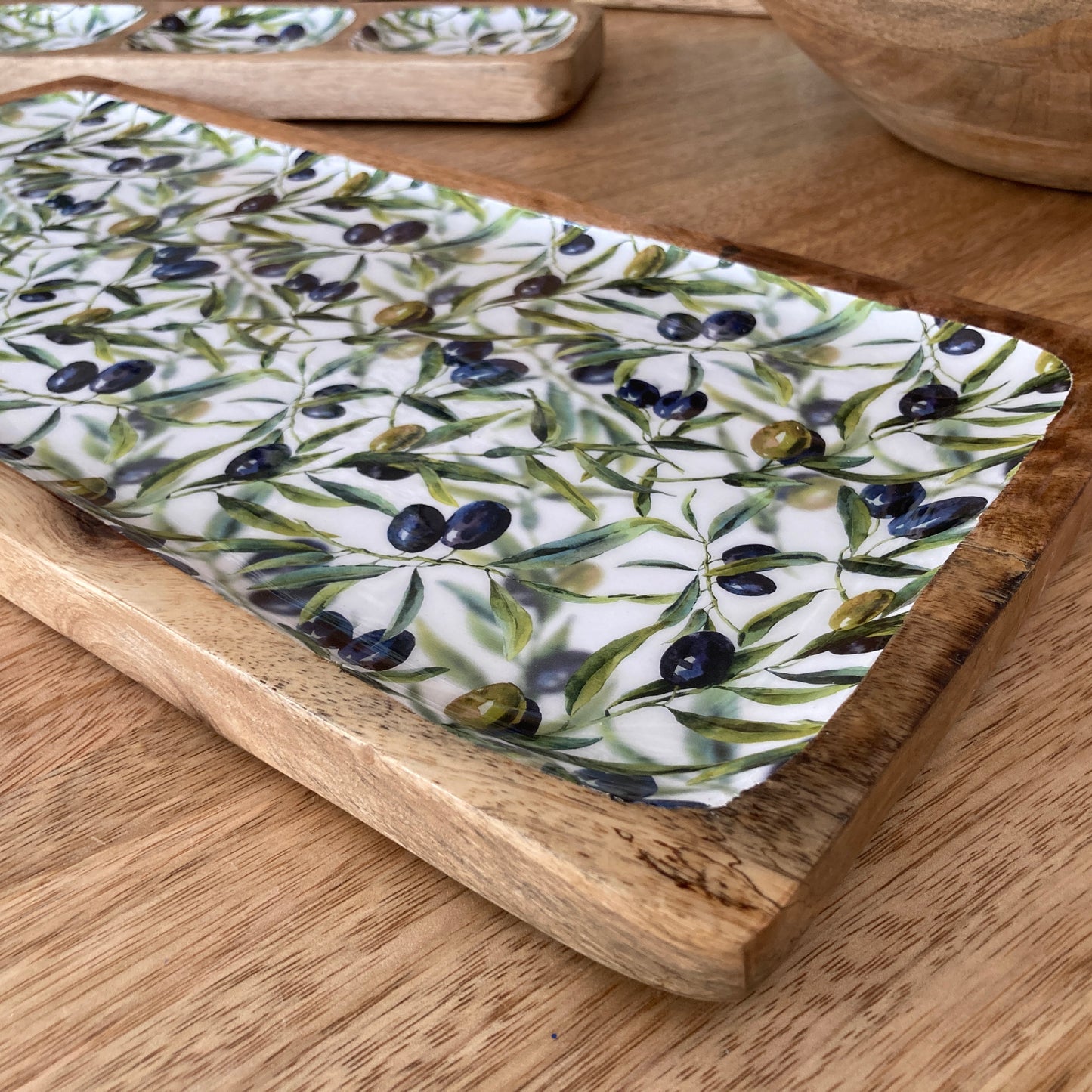 Decorative tray with olive pattern on a wooden surface