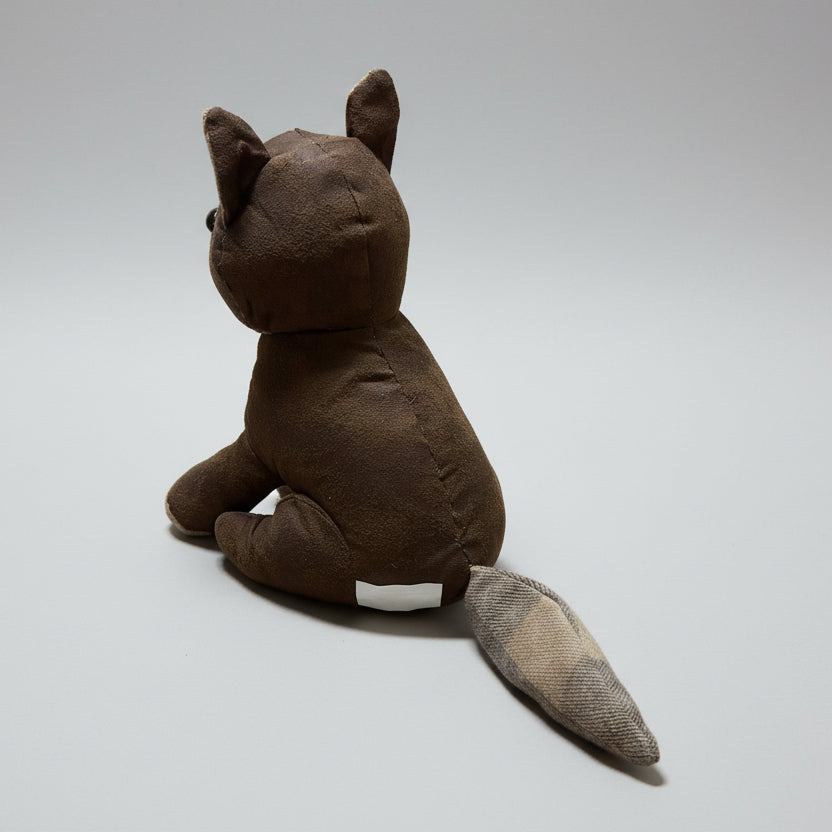 Brown plush toy resembling a fox on a concrete floor