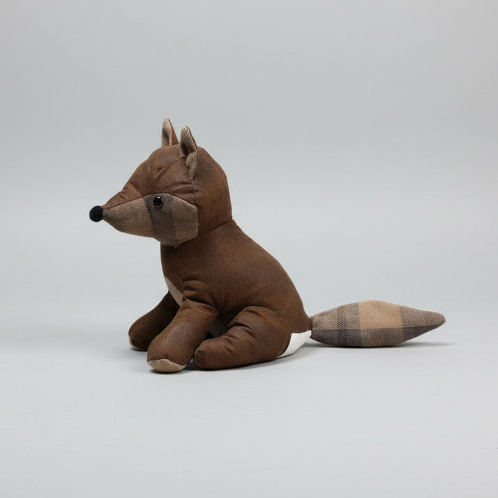 Plush toy fox on a concrete floor with cardboard boxes in the background