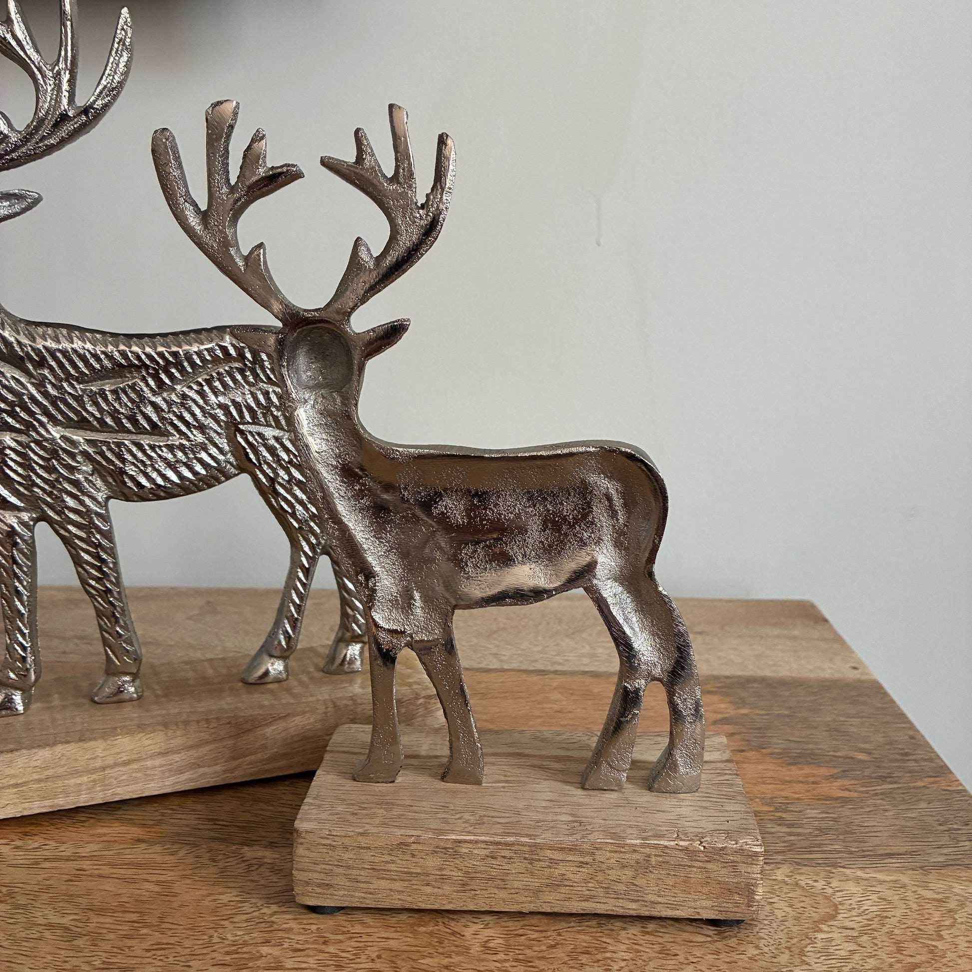 Decorative metal reindeer figurines on wooden bases against a neutral background