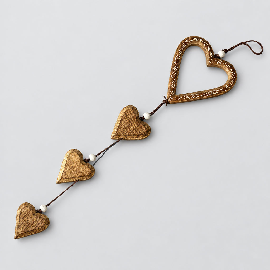 A rustic wooden heart garland with four hanging heart-shaped ornaments connected by a string, displayed on a light wood plank floor.