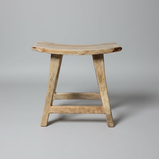 Wooden stool on a wooden floor with cardboard boxes in the background