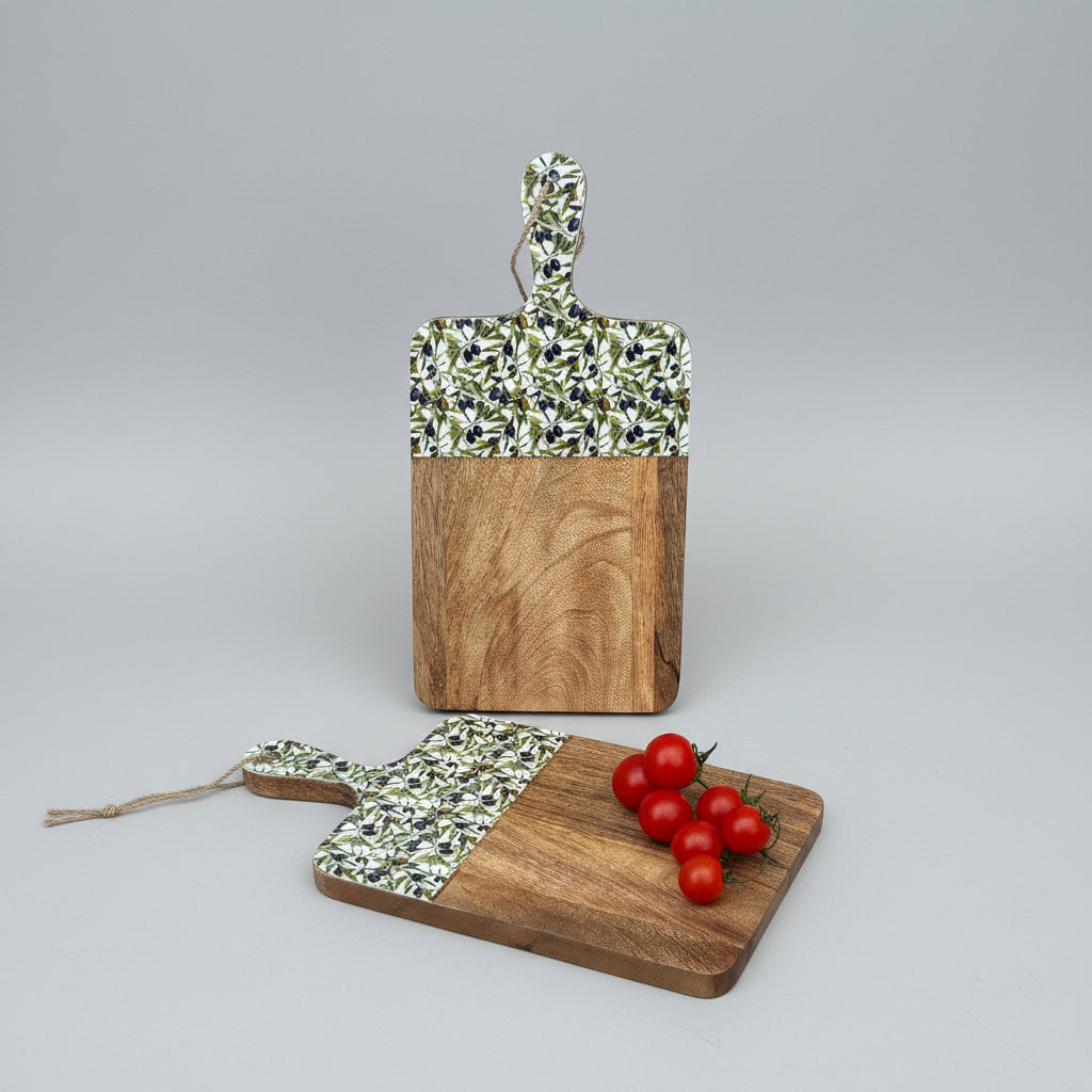 Two wooden cutting boards with patterned handles on a wooden floor with tomatoes.