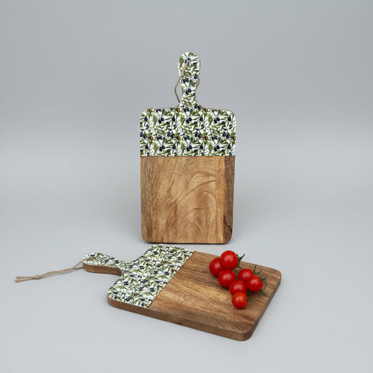 Two wooden cutting boards with patterned handles on a wooden floor with tomatoes.
