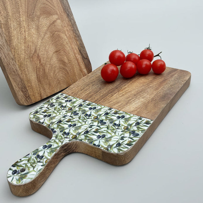 Wooden cutting board with a decorative handle on a light wooden floor.