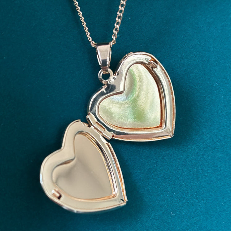Heart-shaped locket on a chain against a teal background
