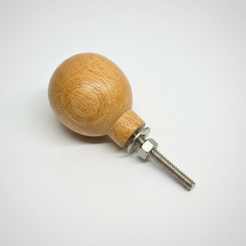 Wooden ball with a metal screw on a gray background
