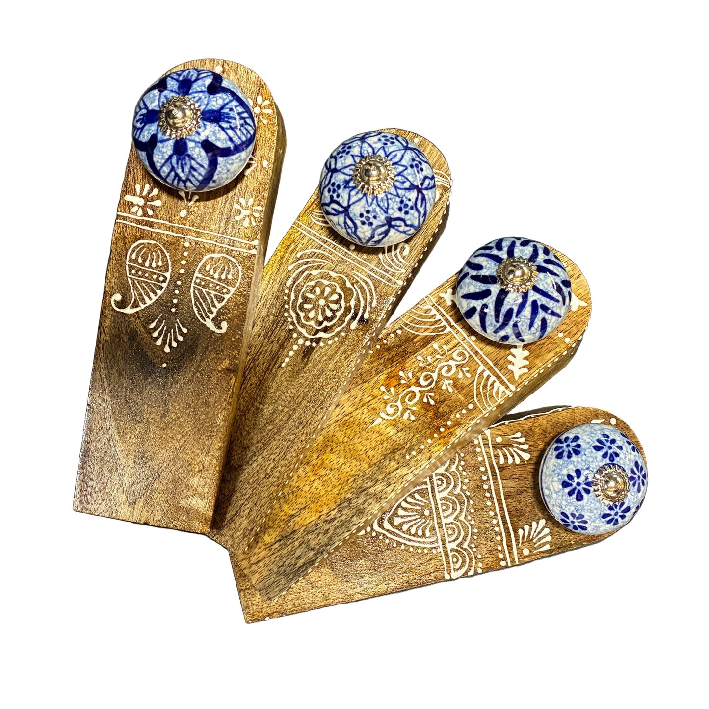 Wooden block with floral designs and blue and white ceramic knobs on a dark surface