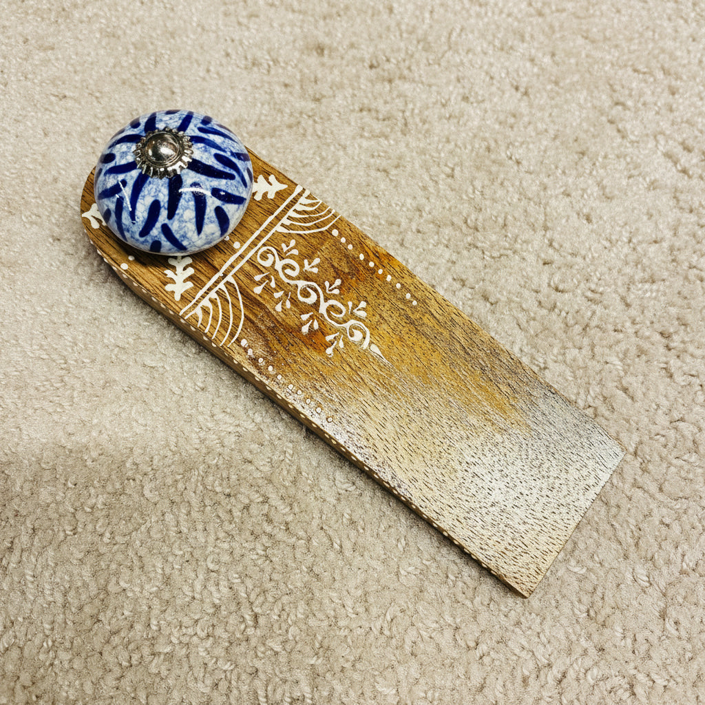 Decorative wooden item with a blue and white ceramic knob on a dark surface