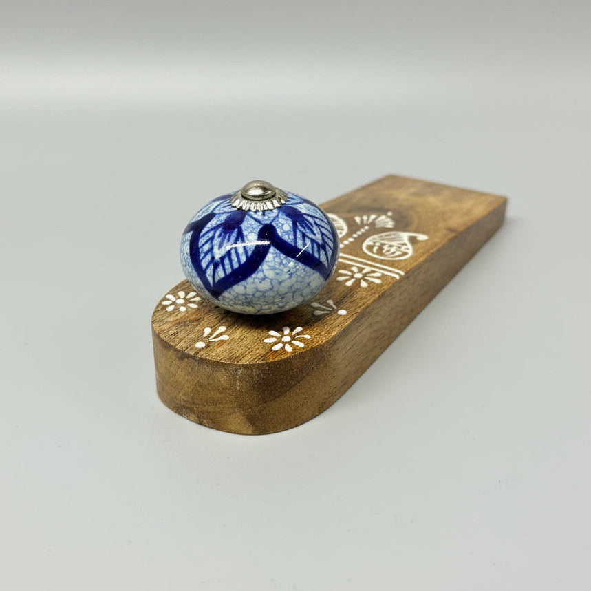 Decorative wooden knob with blue floral design on a gray surface