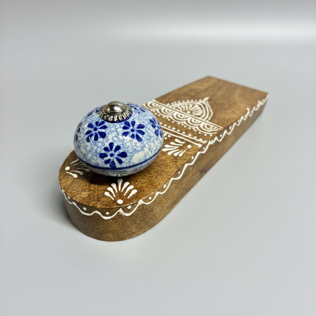 Decorative blue knob with floral patterns on a wooden handle with white designs.