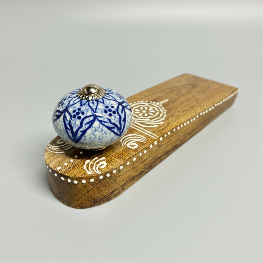 Decorative wooden knob with blue floral pattern on a dark surface