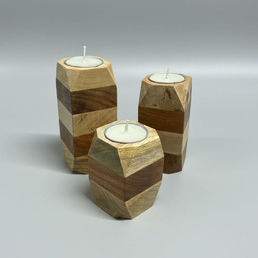 Three wooden candle holders with candles on a dark surface