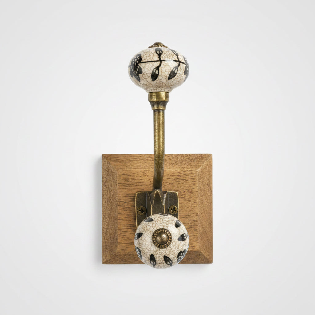 Decorative wall hook with spherical ends on a stand, held by a hand with a blurred background.