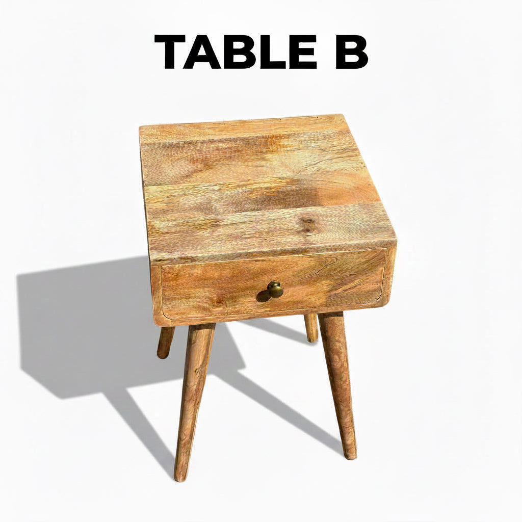 A rustic wooden side table with a single drawer and tapered legs, photographed outdoors on a concrete surface with a fence in the background.