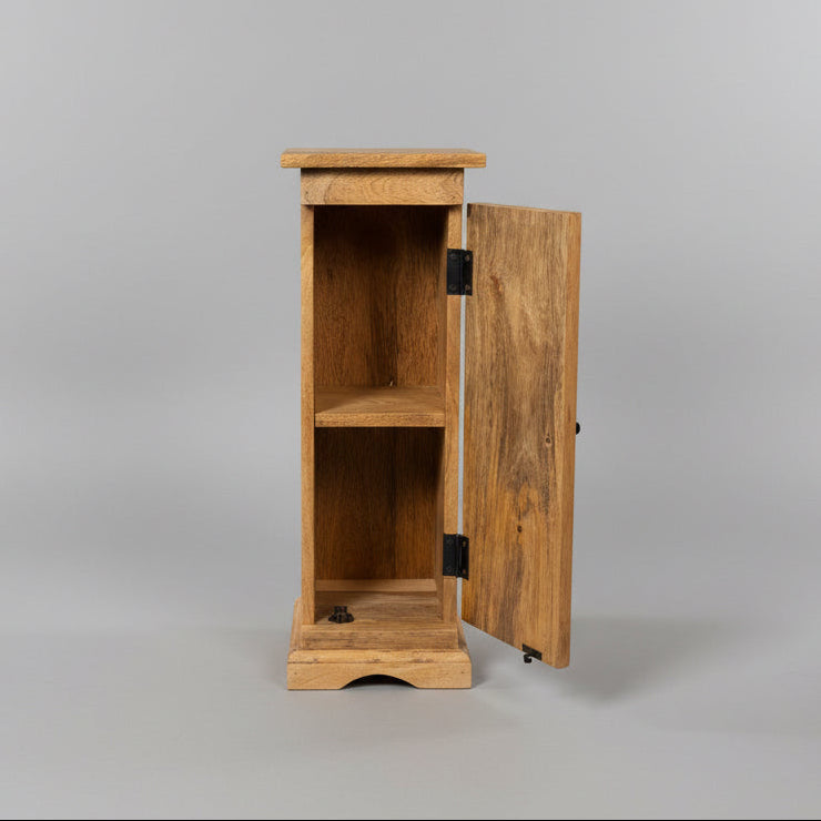 A rustic wooden side cabinet with a single door swung open, showing three interior shelves. The cabinet is made of warm medium-brown wood with black metal hinges, photographed in a workshop environment.