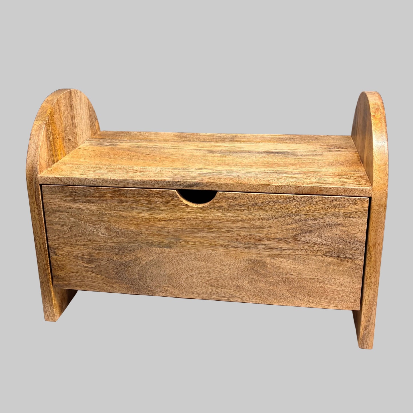 A small wooden storage bench or drawer box with a single front drawer and curved side supports, photographed on a white cloth-covered table in an indoor workshop or storage area.