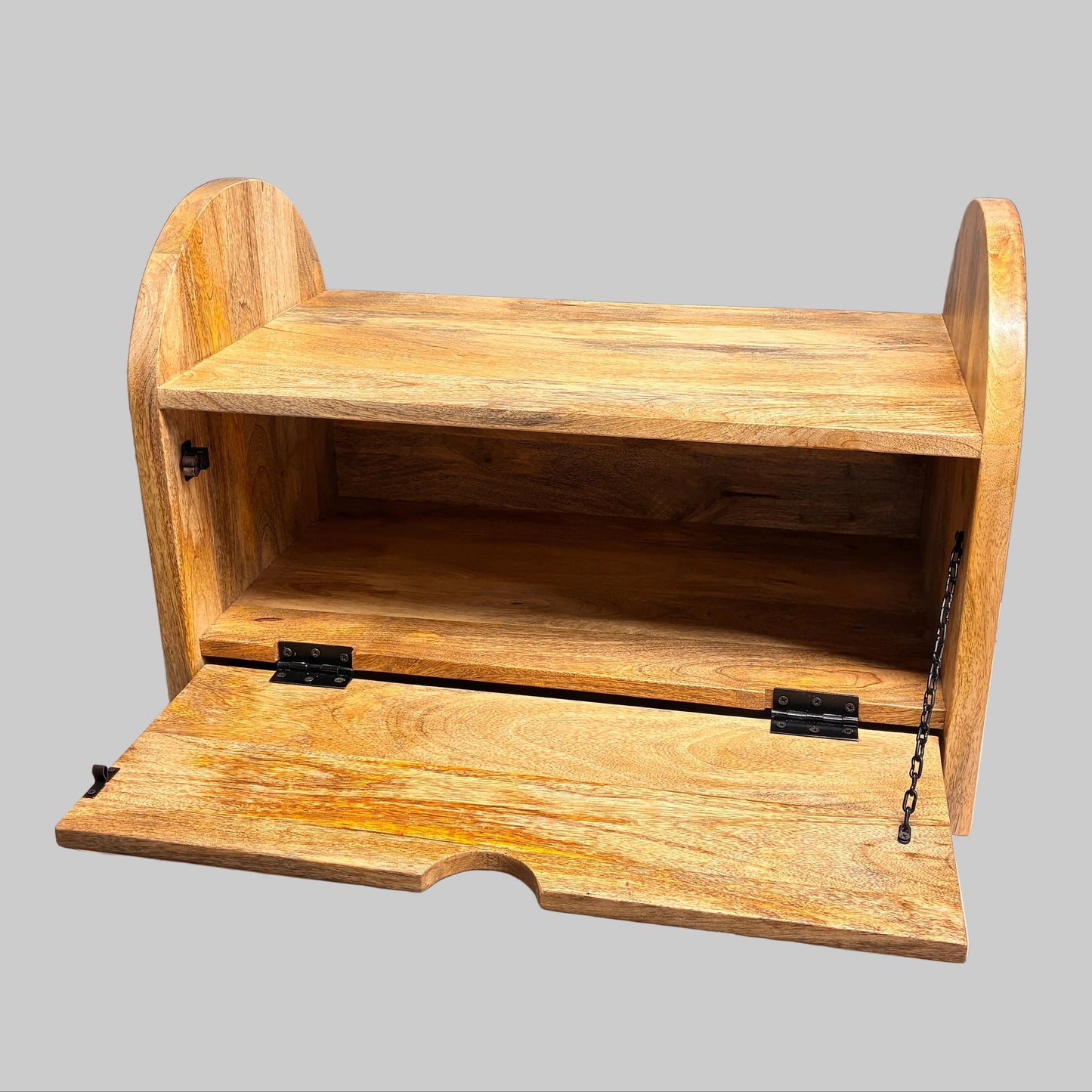 A small wooden storage bench or breadbox-style cabinet with an open front door, shown on a white-covered table against a gray wall.