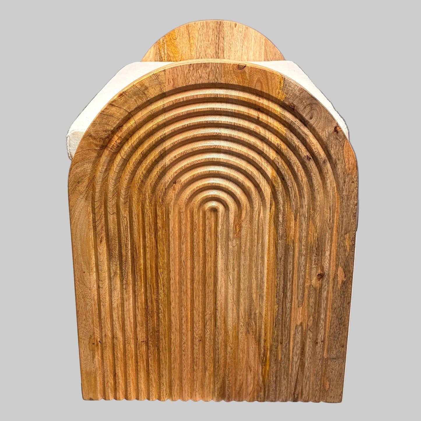 A rustic, arched wooden board with a carved concentric arch pattern, resting on a white cloth-covered table in a workshop or warehouse setting.