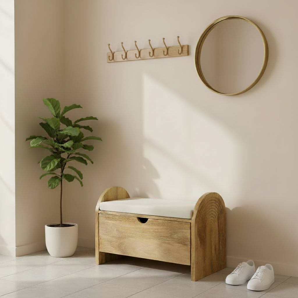 A wooden storage bench with a cream cushioned top and curved arched sides, resting on a workbench in a workshop setting.