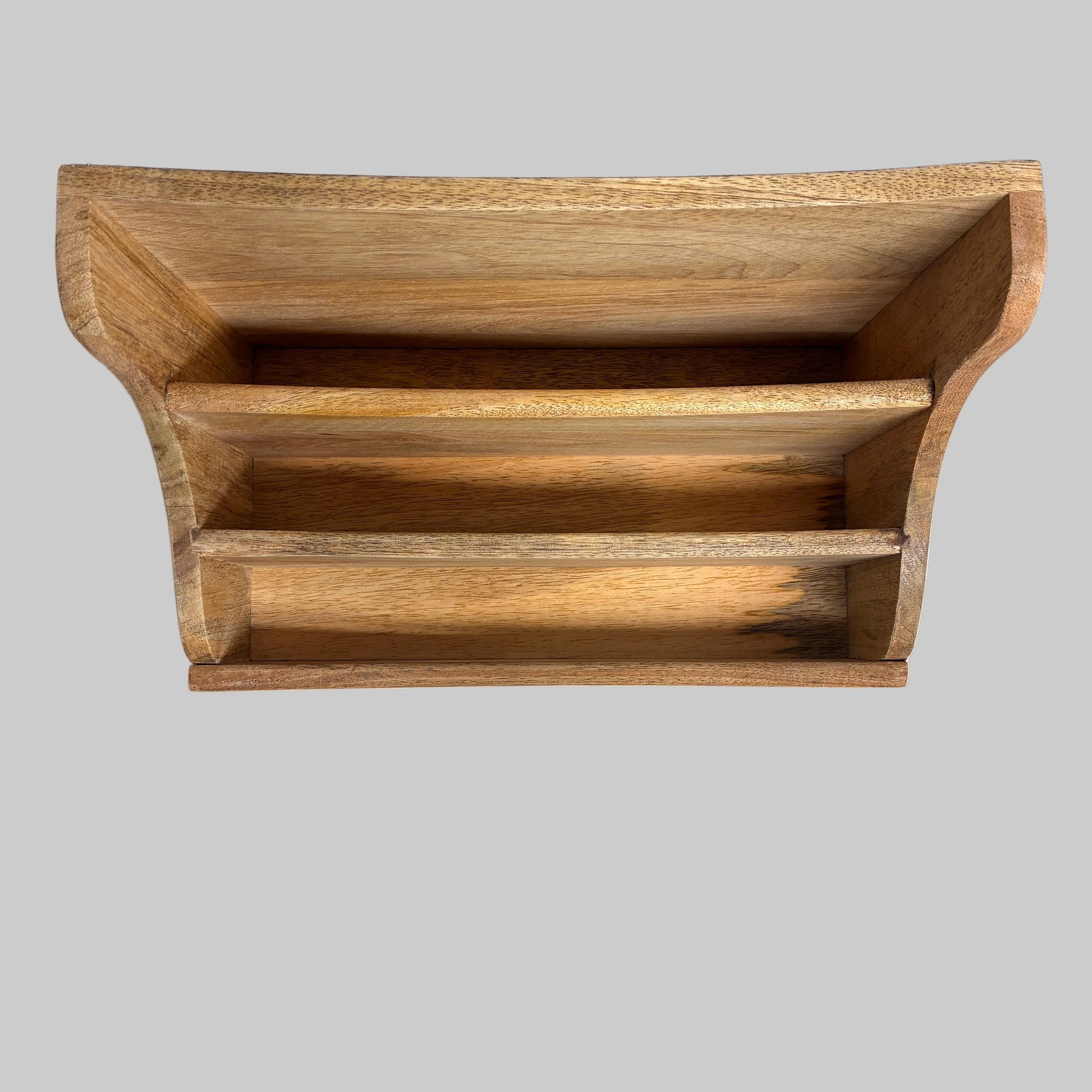 A small wooden organizer tray with three horizontal compartments, shown from above on a light fabric surface against a dark gray background.