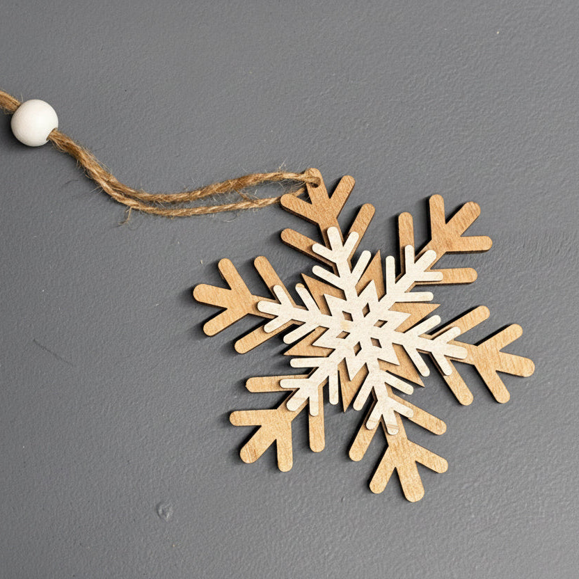 A wooden snowflake ornament with a natural light wood finish and a rustic jute hanging string, displayed on a textured dark gray background.