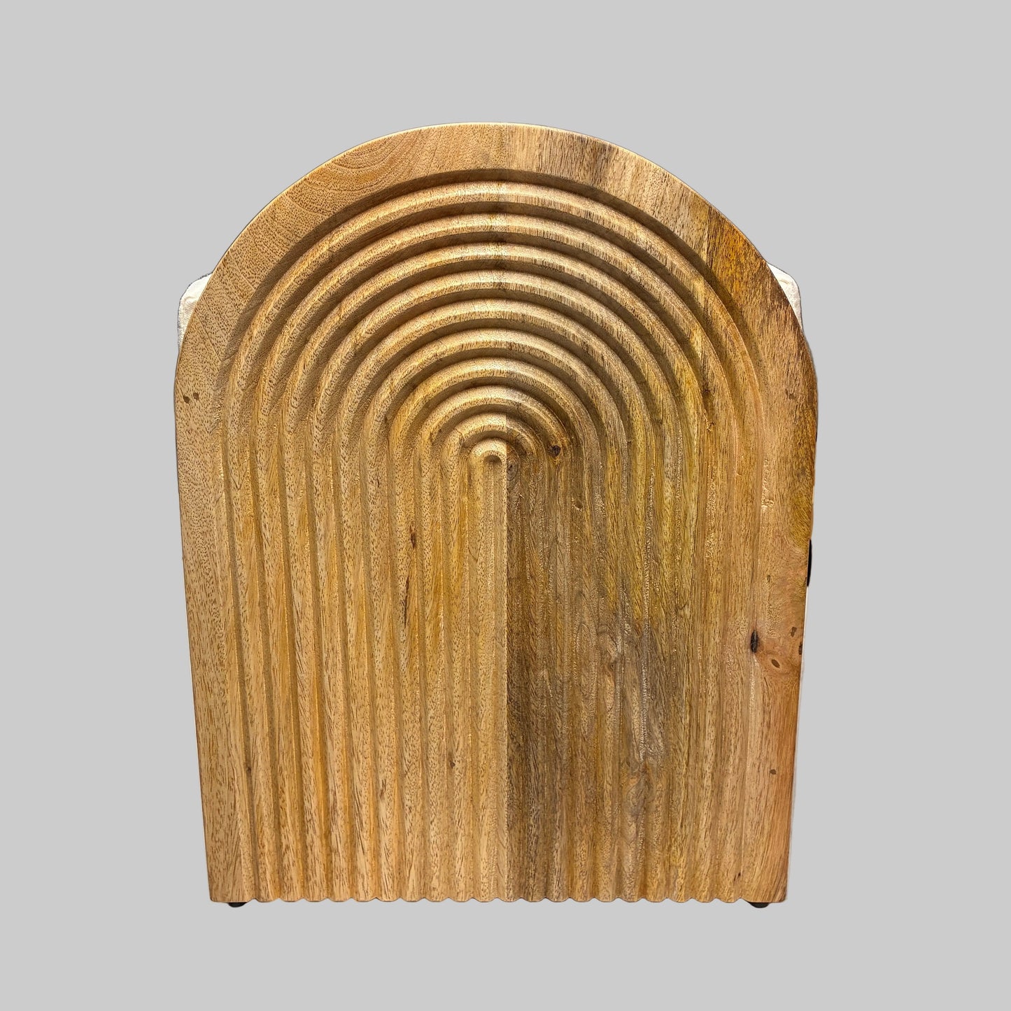 A rustic, hand-carved wooden backrest with an arched ribbed design, resting on a white sheet in a workshop or warehouse setting.